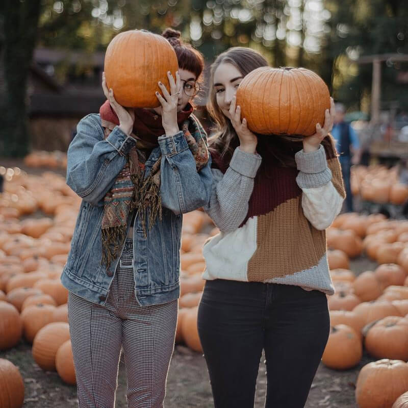 Two Guests Hold Up Pumpkins