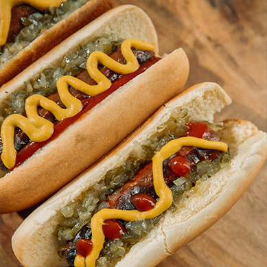 Close Up On Two Hot Dogs With Mustard & Relish